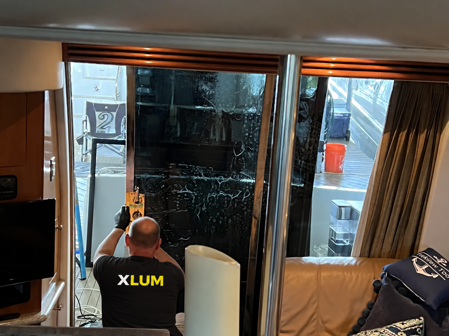 Instalador con camiseta XLUM aplicando película en el vidrio de una embarcación